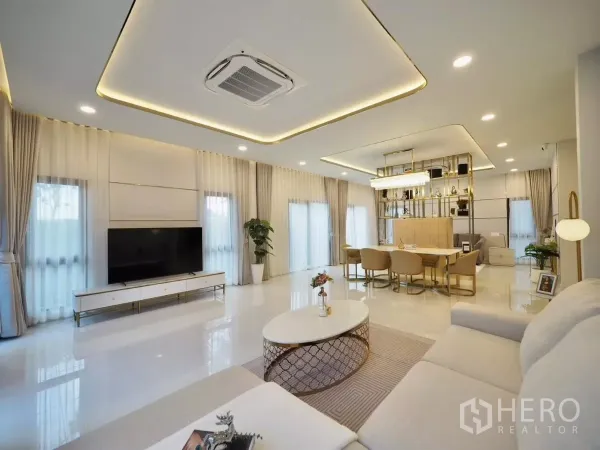 独立式住宅 出租在Bang Phli, Samut Prakan - 开放式客餐厅，电视墙、水晶灯和落地窗帘。