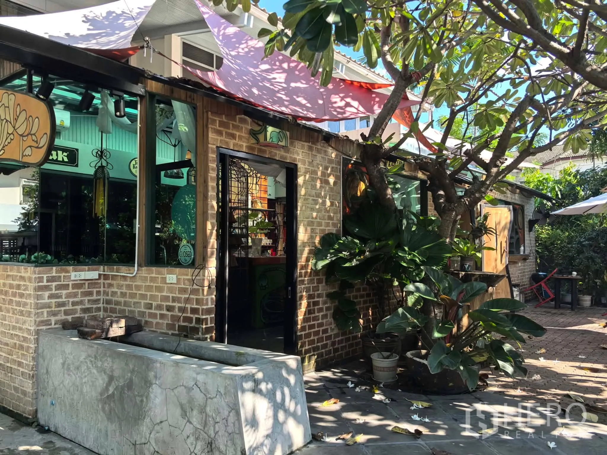 独栋房屋 for rent in Watthana, Bangkok - 砖墙露台外立面，推拉门与繁茂盆栽在树荫下。
