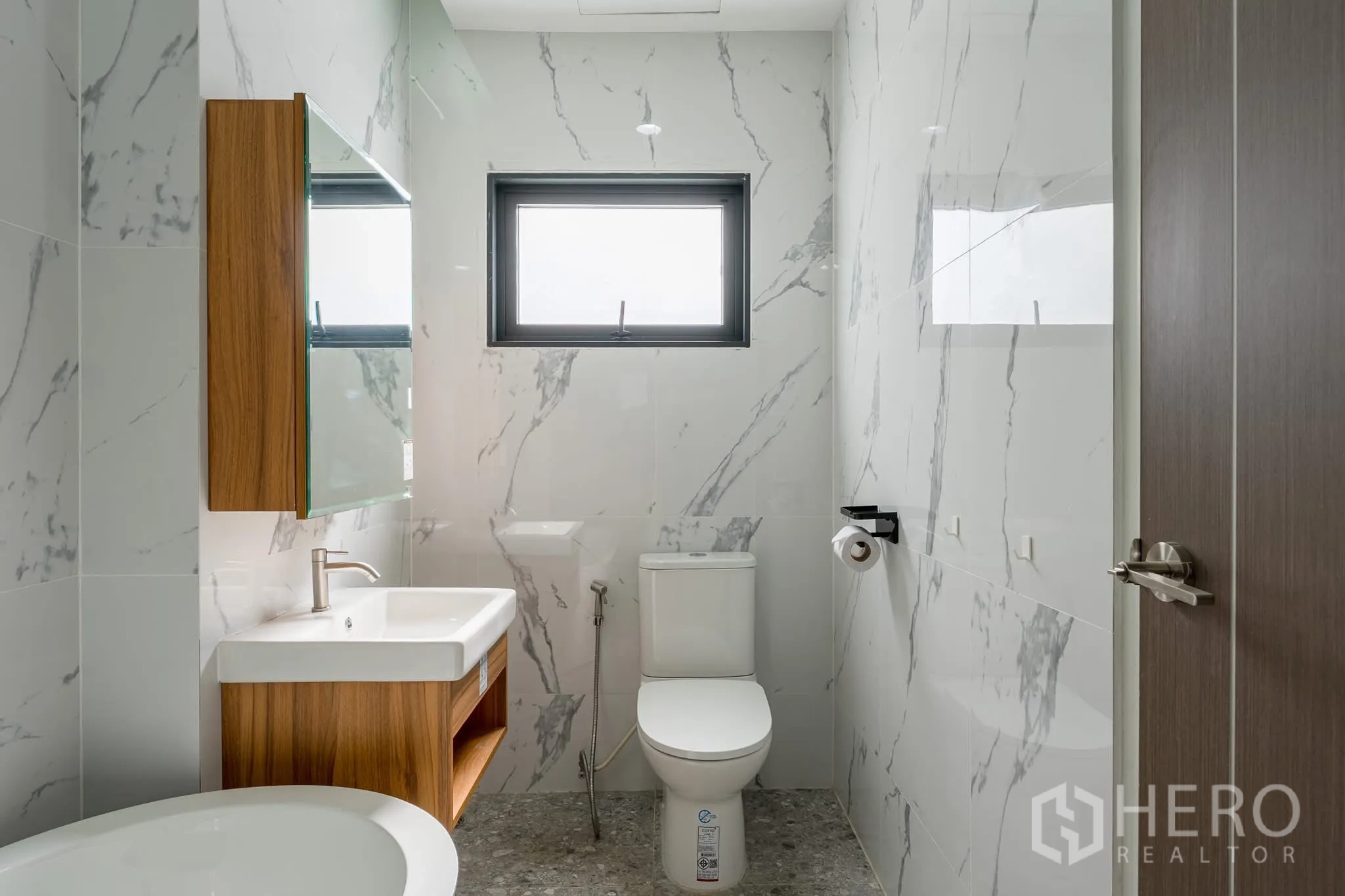 Home Office for rent in Khlong Toei, Bangkok - Bathroom with marble-effect walls, wood vanity cabinet, toilet and window.