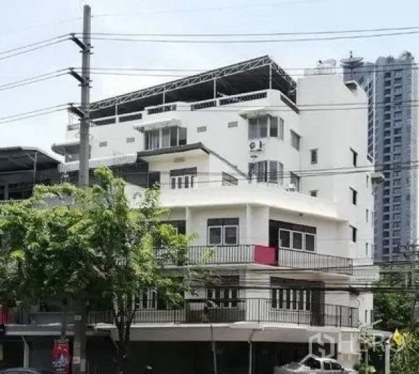 Shophouse for rent in Khlong Toei, Bangkok - Multi-storey corner shophouse with balconies along a busy Bangkok street.