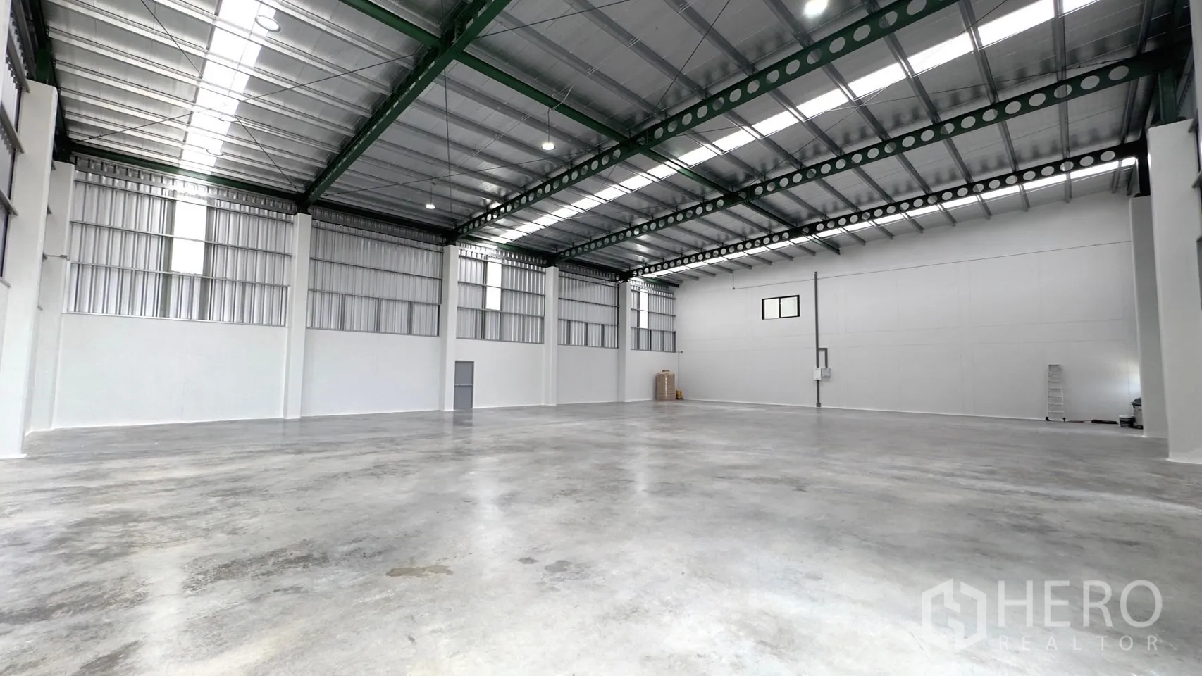 Factory for rent or sale in Bang Yai, Nonthaburi - Expansive column-free production floor with skylights and white walls.
