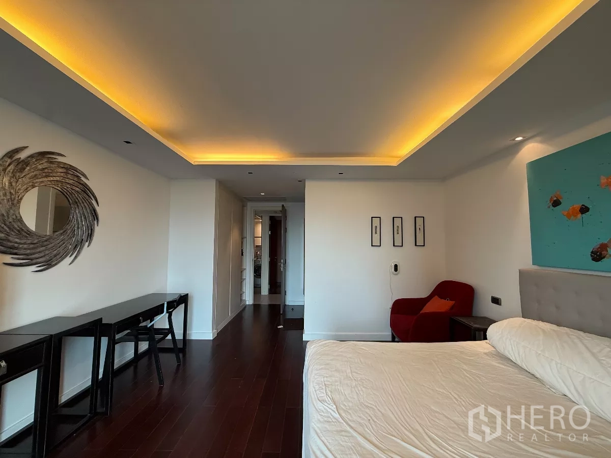 公寓 出租在Phaya Thai, Bangkok - 主卧室，吊顶灯带、深色木地板、床与休闲椅。