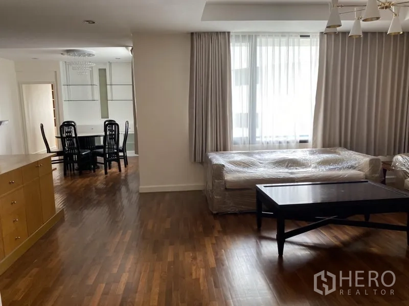 Condominium for rent or sale in Sathon, Bangkok - Bright lounge with floor-to-ceiling curtains and an adjoining dining zone in a 2-bedroom condo.