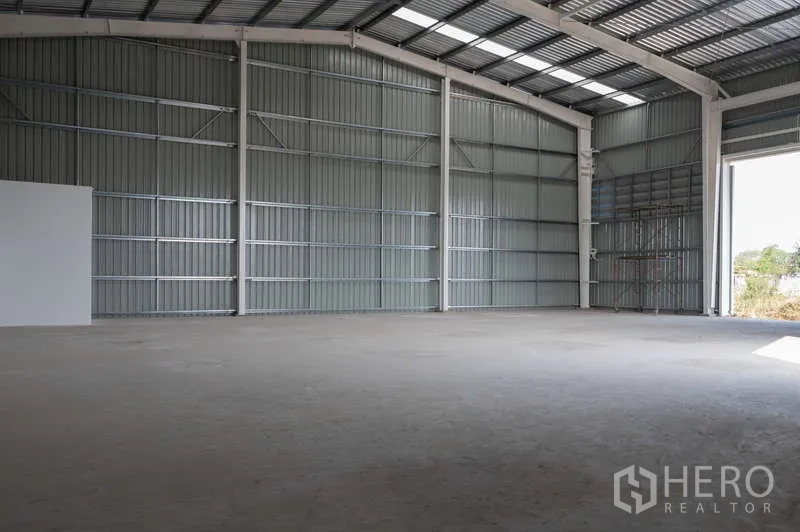 Warehouse for rent in Khlong Luang, Pathum Thani - Wide column-free storage hall under an arched metal roof with translucent panels.