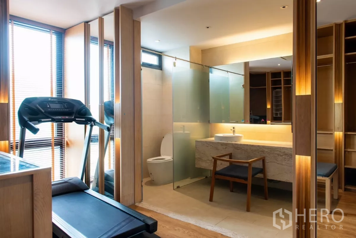 Townhouse for rent in Lat Phrao, Bangkok - Ensuite bathroom with frosted glass panels and nearby treadmill.