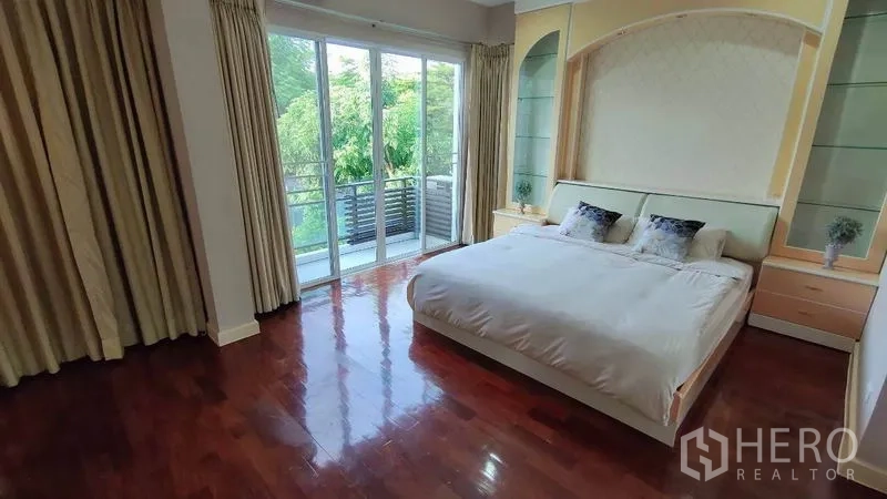Detached House for rent in Bang Phli, Samut Prakan - Master bedroom with king bed, wood floors and balcony access through sliding doors.
