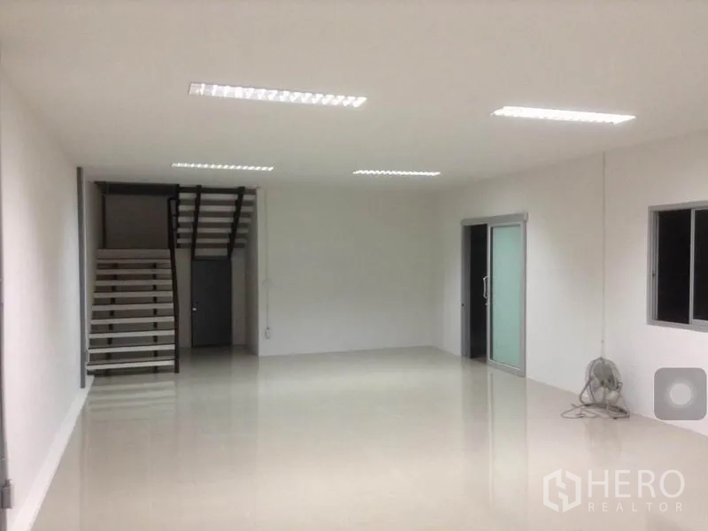 Warehouse for rent in Bang Kapi, Bangkok - Open-plan interior showing staircase, windows and a glass door suitable for office or storage use.