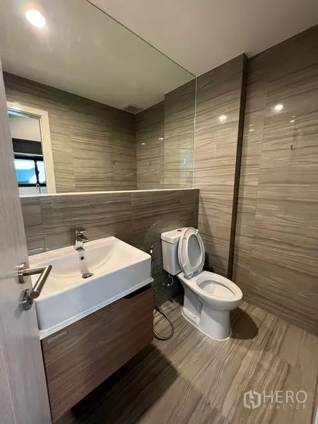 Townhouse for rent in Suan Luang, Bangkok - Modern bathroom with a large mirror, square basin, wooden vanity and toilet.