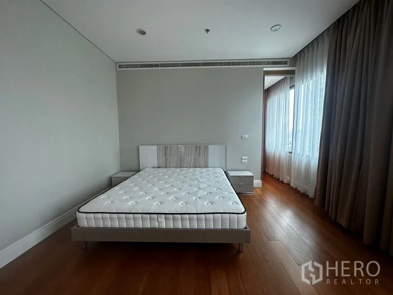 Condominium for rent in Khlong Toei, Bangkok - Bright master bedroom with bedframe, bedside tables and sheer curtains.