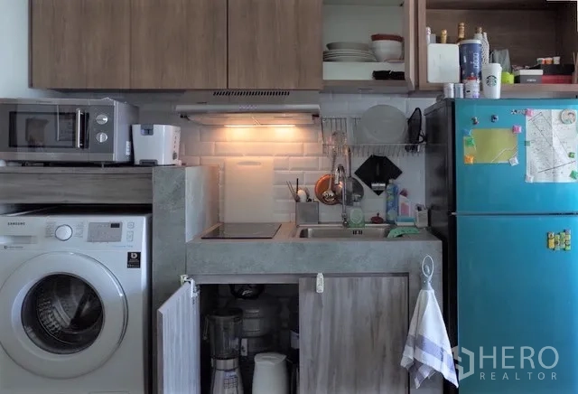 Condominium for rent in Khlong Toei, Bangkok - Compact kitchenette with stove, hood, sink, fridge and washing machine.