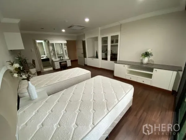 Condominium for rent in Watthana, Bangkok - Twin-bed room from another angle showing built-in storage, wood floors, and ensuite access.