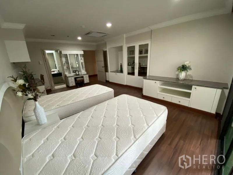 Condominium for rent in Watthana, Bangkok - Twin-bed room from another angle showing built-in storage, wood floors, and ensuite access.