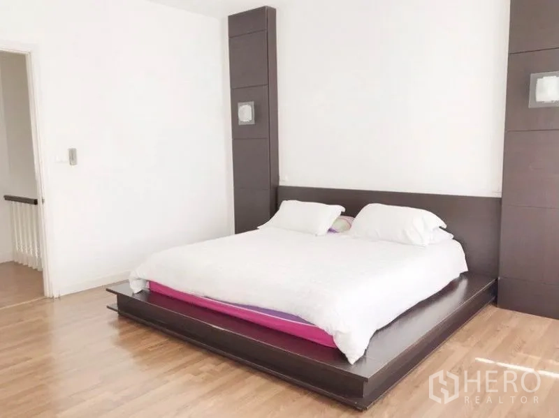 联排别墅 出租在Prawet, Bangkok - 主卧配平台床与白色床品，木地板，简约舒适。