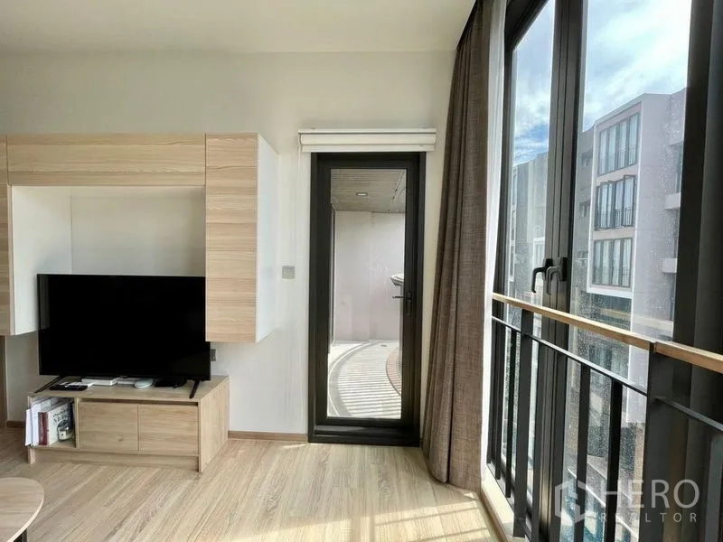 公寓 出租或出售在Watthana, Bangkok - Kawa Haus 公寓明亮客厅，电视柜、浅木地板与阳台门，采光充足。