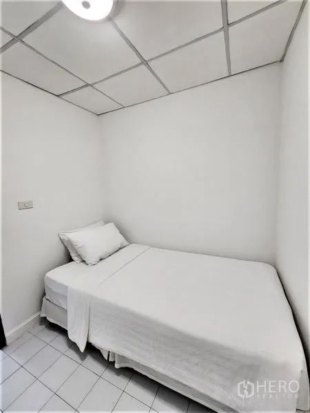 Condominium for rent in Bang Rak, Bangkok - Small maid’s or utility room with a single bed, white tile floor and drop ceiling.