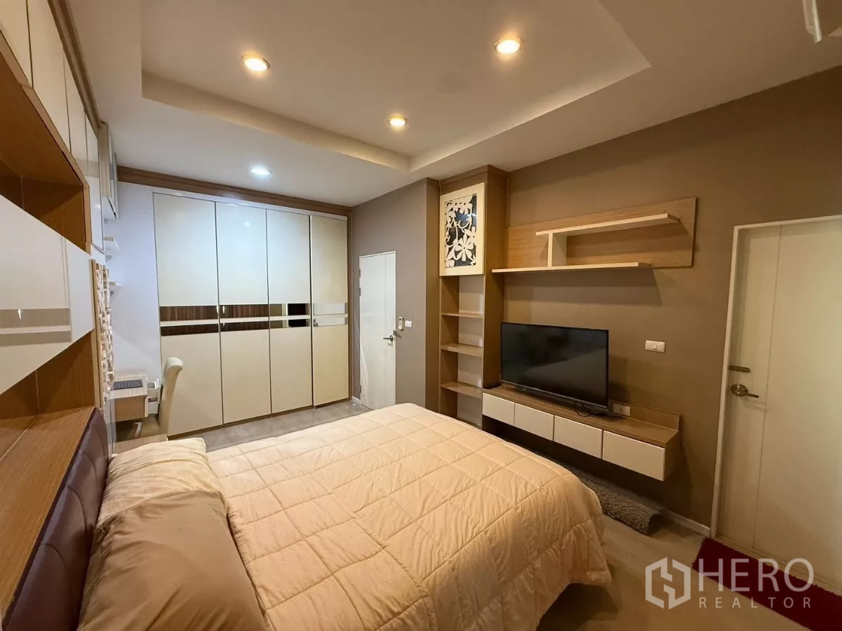 Townhouse for rent in Suan Luang, Bangkok - Second bedroom opposite view showing TV wall and full-height storage.