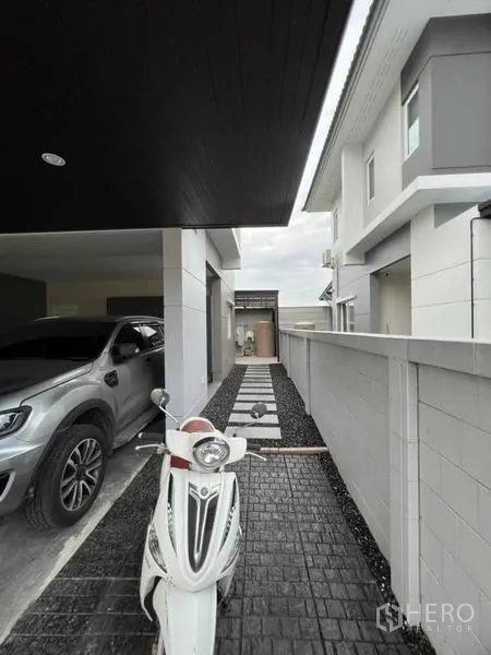 独立式住宅 出租或出售在Lat Krabang, Bangkok - 侧院步道，连接车棚并停放一辆机车。