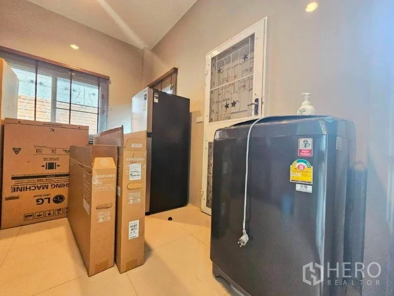 Detached House for rent in Chatuchak, Bangkok - Utility area with washing machine, refrigerator and storage boxes near the rear door.