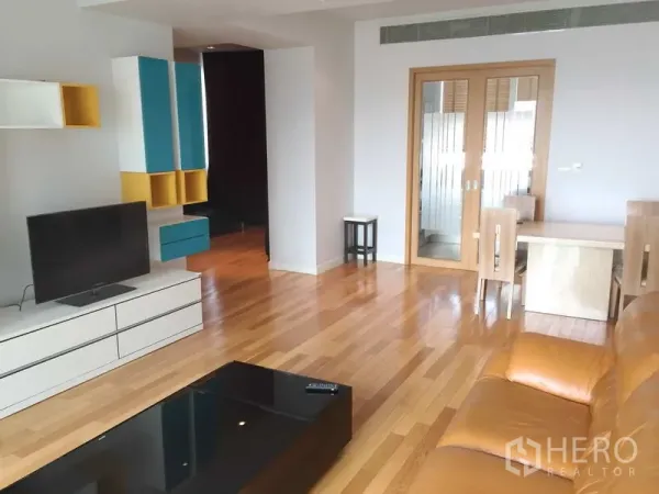 Condominium for sale in Khlong Toei, Bangkok - Open-plan lounge and dining area with built-in TV console, colorful wall cabinets and wooden floors.