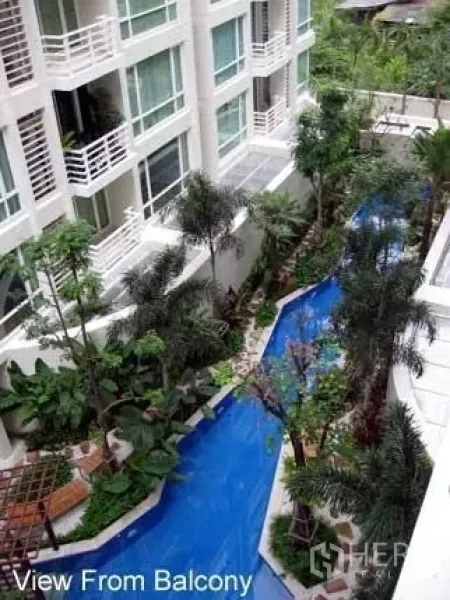 คอนโด ให้เช่าในKhlong Toei, Bangkok - มุมมองจากระเบียงเห็นสระว่ายน้ำสไตล์รีสอร์ทคดเคี้ยวท่ามกลางสวนเขตร้อนและอาคารคอนโดโลว์ไรส์