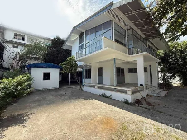 Detached House for rent in Watthana, Bangkok - Corner view of a white two‑storey house with balcony and covered terrace.