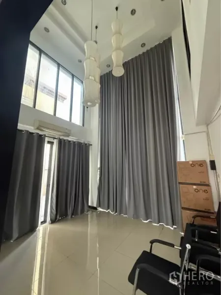 带办公室的家 出租在Wang Thonglang, Bangkok - 挑高大堂，落地窗旁悬挂吊灯与厚窗帘。