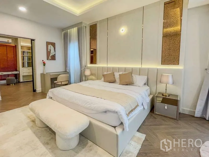 Detached House for rent in Saphan Sung, Bangkok - Elegant master bedroom with upholstered headboard, soft lighting and access to a walk-in area.