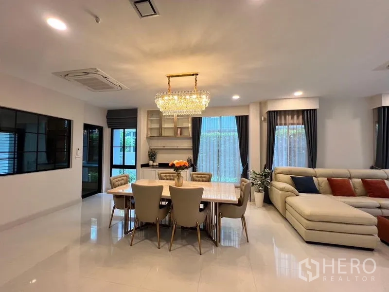 Detached House for rent or sale in Saphan Sung, Bangkok - Dining area with crystal chandelier and eight-seat table adjoining the living room.