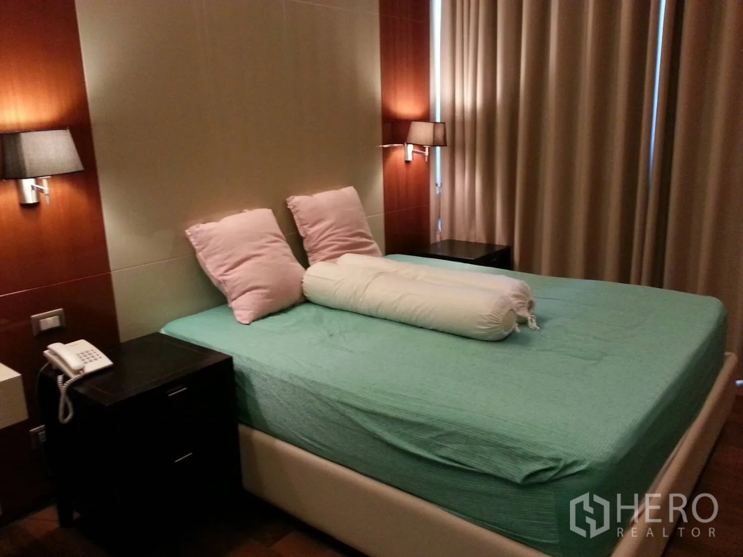 Condominium for rent or sale in Khlong Toei, Bangkok - Primary bedroom featuring a large bed, wall lamps, bedside tables and blackout curtains.