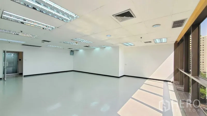 办公空间 出租在Watthana, Bangkok - 转角办公室内景，窗墙采光充足，亮面地坪、玻璃入户门与吊顶出风口。