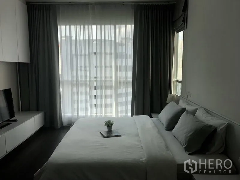 公寓 出租在Pathum Wan, Bangkok - 明亮卧室，落地窗与纱帘，电视柜，大床与浅色床品。