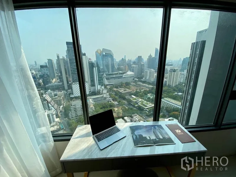 公寓 出租在Pathum Wan, Bangkok - 从卧室窗外俯瞰全景城市视野与大理石台面书桌。