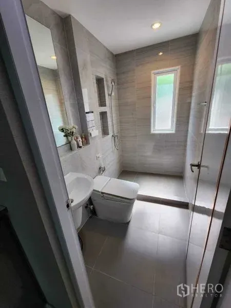 Detached House for rent in Bang Khen, Bangkok - Modern bathroom with gray tiles, windowed walk-in shower, toilet and basin.