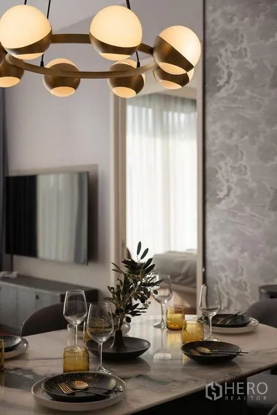 Condominium for rent in Watthana, Bangkok - Close-up of a marble dining table set under a gold globe chandelier in a Thonglor condominium.