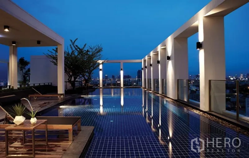 Condominium for rent or sale in Phaya Thai, Bangkok - Rooftop infinity-style pool at dusk with seating and panoramic skyline.