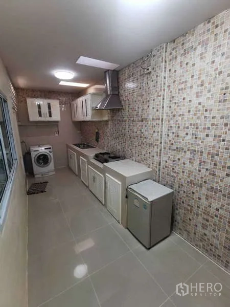 Townhouse for rent in Chatuchak, Bangkok - Galley kitchen with mosaic backsplash, gas hob, hood, cabinets and washer.