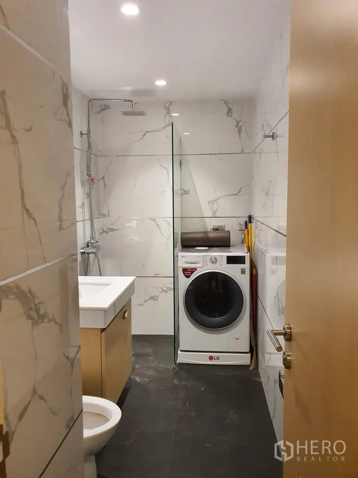 Condominium for rent in Watthana, Bangkok - Bathroom with rain shower, vanity and an LG washer-dryer set against marble-look tiles.