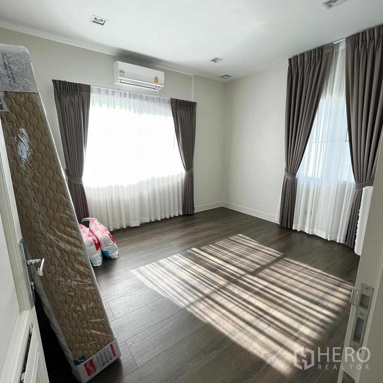 Detached House for rent or sale in Bang Khen, Bangkok - Sunlit empty bedroom with wood floors, curtains and air‑con.