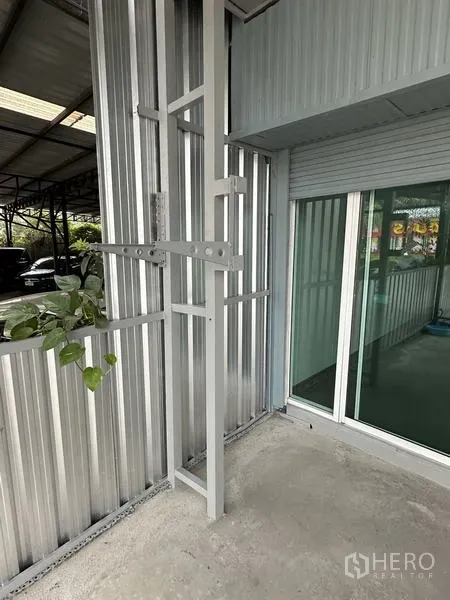 Warehouse for rent in Lat Krabang, Bangkok - Detail of exterior wall with glass office entrance beside a rolling shutter at the warehouse.