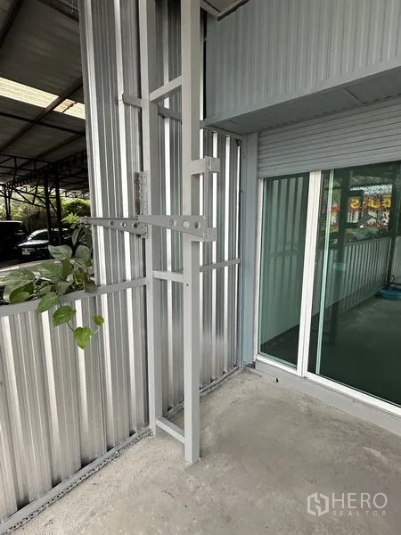 Warehouse for rent in Lat Krabang, Bangkok - Detail of exterior wall with glass office entrance beside a rolling shutter at the warehouse.