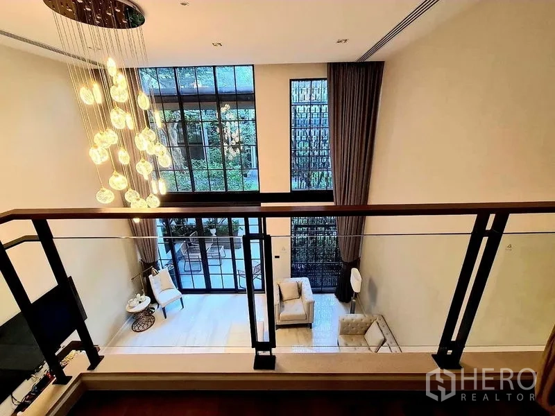 联排别墅 出租在Watthana, Bangkok - 从夹层俯瞰挑高客厅，通高落地窗与吊灯