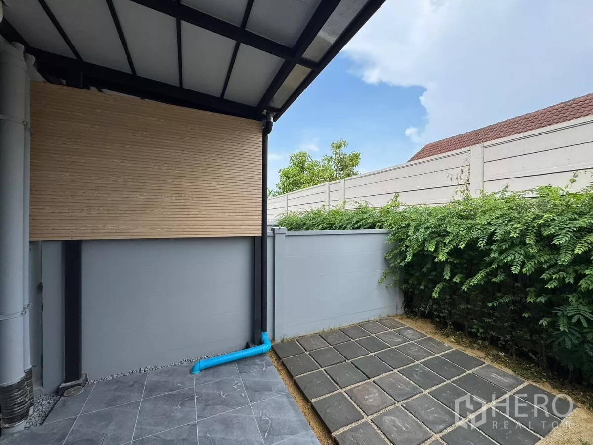 Townhouse for rent in Bang Phli, Samut Prakan - Back patio with tiles, privacy wall and hedge along the boundary.