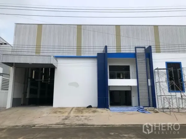 工厂 出租或出售在Samut Prakan - 邦普利区现代工厂外立面，蓝色点缀，带办公入口与宽阔装卸口。