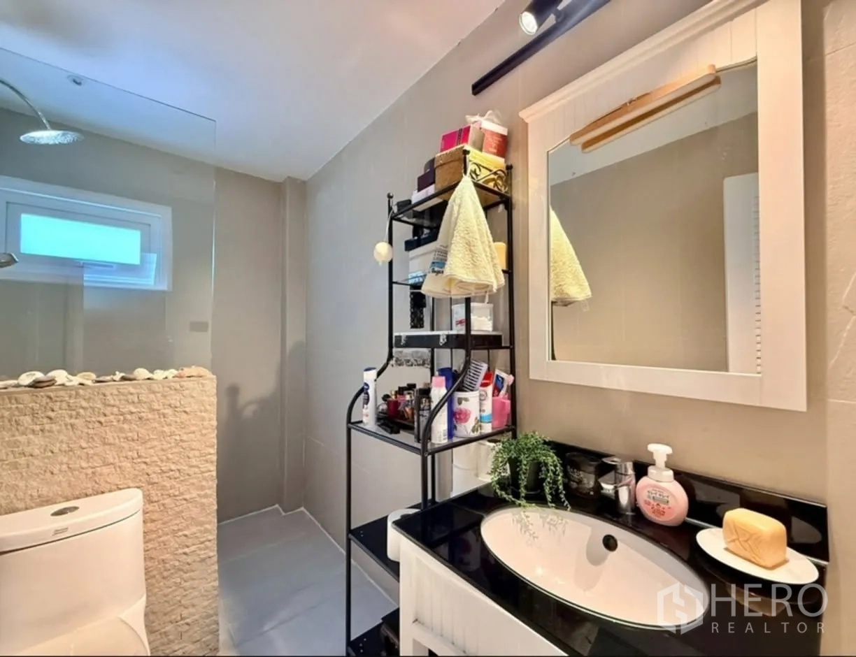 Detached House for rent in Phra Khanong, Bangkok - Modern bathroom with vanity, mirror, and a walk-in shower behind glass.