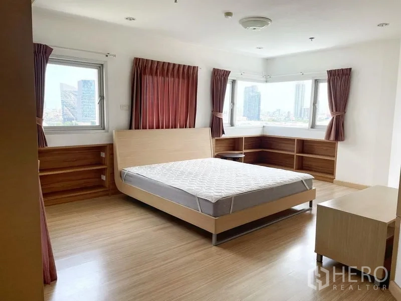 Condominium for rent in Khlong Toei, Bangkok - Spacious bedroom with built-in shelves, large windows and skyline views.