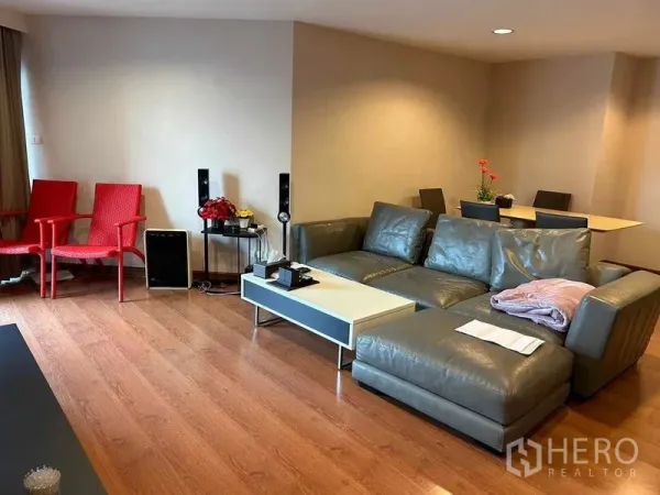 คอนโด ขายในHuai Khwang, Bangkok - ห้องนั่งเล่นแบบเปิดโล่ง โซฟาหนังสีเทา โต๊ะกลางสีขาว พื้นไม้ และมุมทานอาหาร