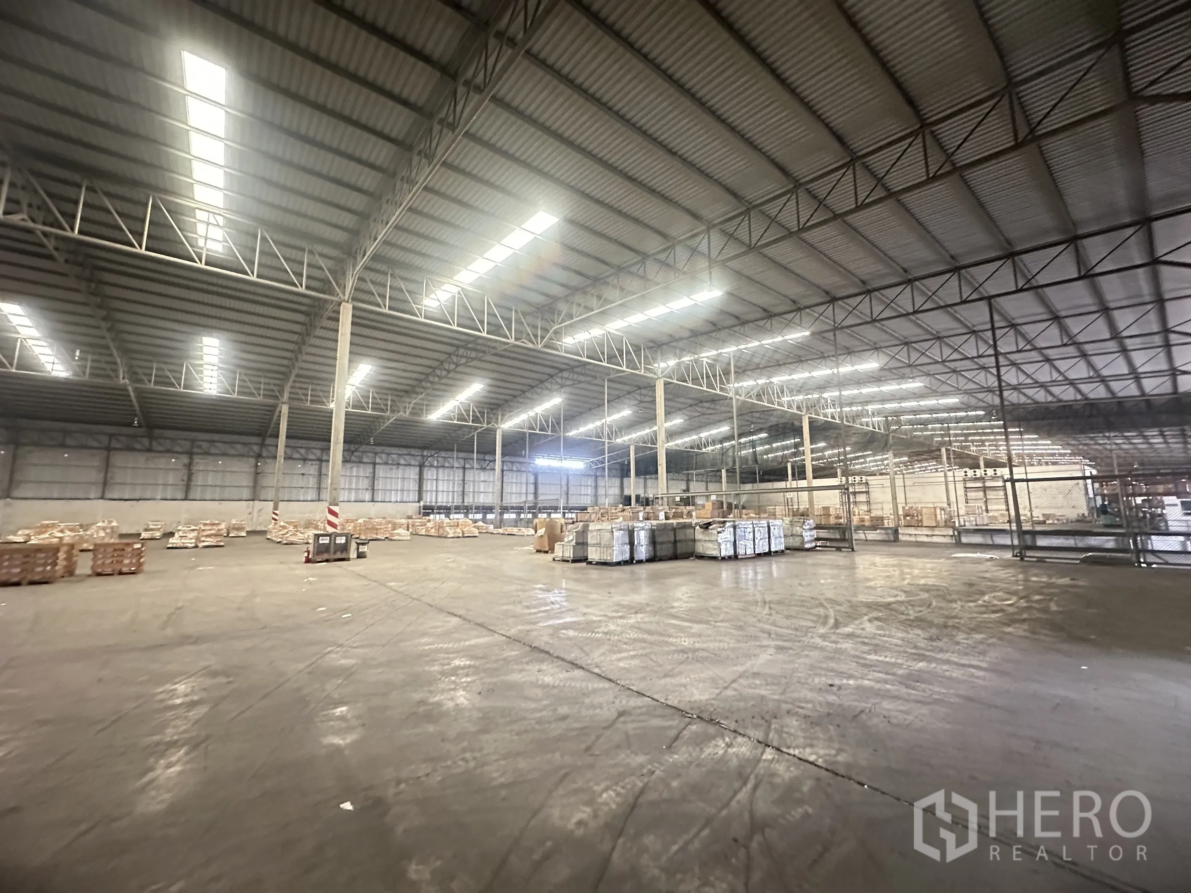 Warehouse for rent in Bang Pa-in, Phra Nakhon Si Ayutthaya - Large floor area with steel structure, fenced storage section, and palletized goods.