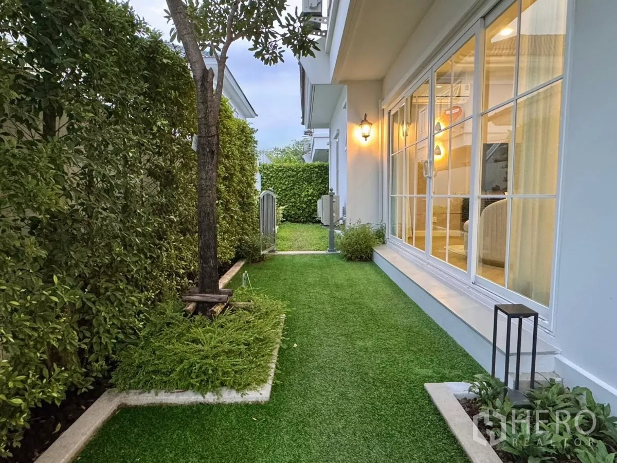 Detached House for rent in Bang Phli, Samut Prakan - Side lawn with hedges and sliding doors opening from the living room.