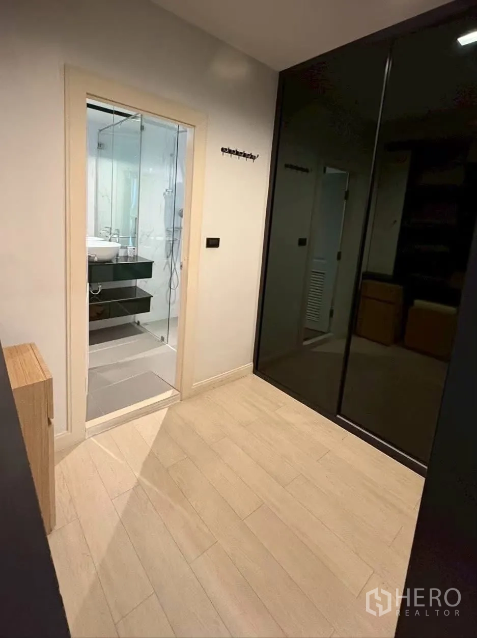 ทาวน์เฮาส์ for rent in Pathum Wan, Bangkok - ห้องพื้นไม้สีอ่อน ตู้เสื้อผ้าบานกระจกสีดำ และประตูเข้าสู่ห้องน้ำ.