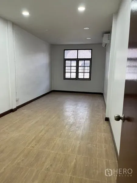 Townhouse for rent in Din Daeng, Bangkok - Long bedroom with wood-look flooring, recessed ceiling lights, and a window for natural light.